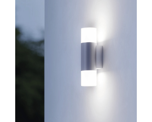 Lysande utomhusvägglampa med cylindrisk design på en fasad