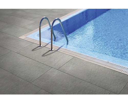 Pool med grå terrassplattor och stege i rostfritt stål