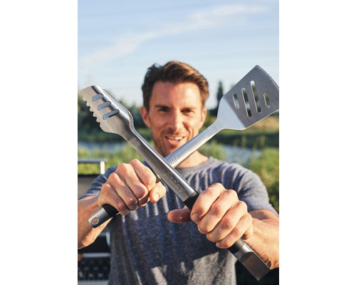 Man håller grilltång och stekspade korsade mot kameran.