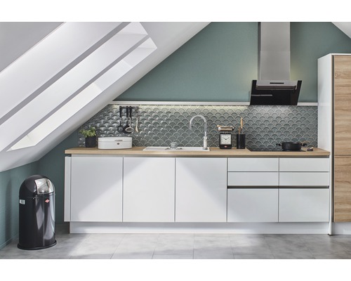 Kök med vita skåp, diskho, köksfläkt och papperskorg under ett takfönster