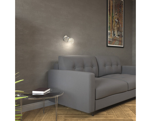 Vardagsrum med grå soffa, vägglampa och sidobord