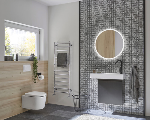 Modernt badrum med vägghängd toalett, handfat, spegel med belysning och handdukstork