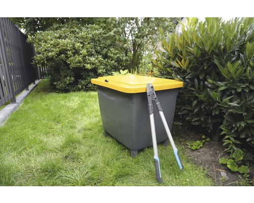 Trädgårdsscen med kompost och trädgårdssax på gräsmatta