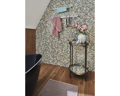 Badrum med mosaikvägg, badkar, handdukar och sidobord