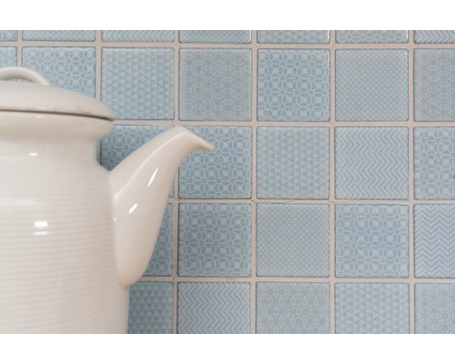 Dekorativa kvadratiska väggplattor med mönster bakom en tekanna