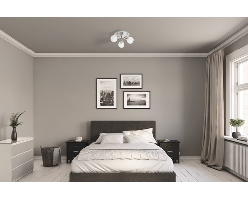 Sovrum med säng, sängbord, byrå, taklampa och väggdekorationer