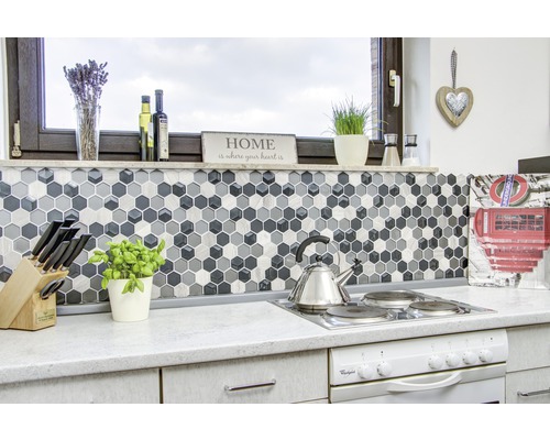 Köksscen med mosaikplattor i hexagonform, spis och köksredskap.