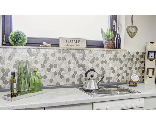 Köksscen med mosaikplattor i hexagonmönster, spishäll och dekorationer.