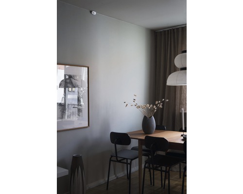 Matsal med träbord, stolar, dekoration och en inramad bild på väggen.