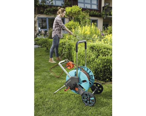 Kvinna använder Gardena trädgårdsslangvagn i trädgården