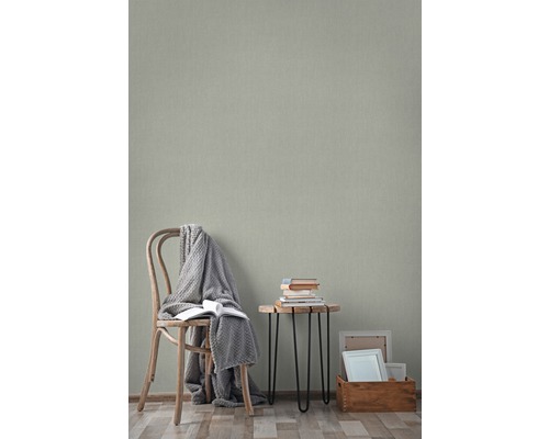 Vardagsrum med trästol, sidobord med böcker och mönstrad tapet