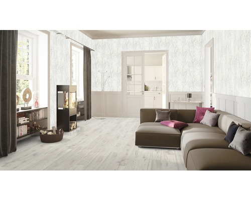 Vardagsrum med soffa, öppen spis och väggtapet med växtmönster.