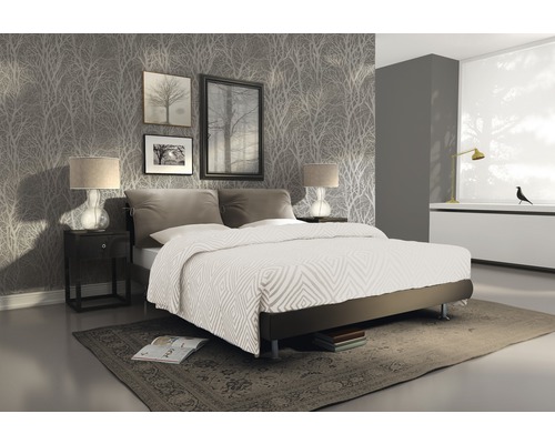 Sovrum med dubbelsäng, nattduksbord, lampor, tavlor och mönstrad tapet