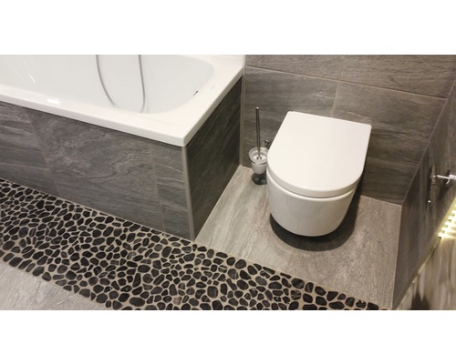 Badrum med badkar, toalett och stengolv