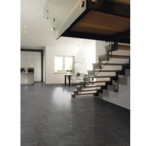 Ljust rum med kök, trappa och grått klinkergolv.