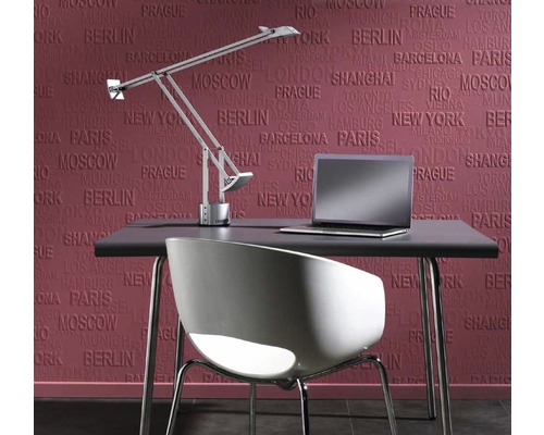 Skrivbord med lampa, stol och bärbar dator framför en tapet med stadsnamn