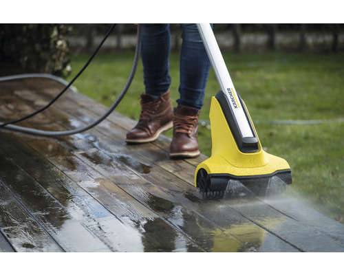 Person rengör en träterrass med en Kärcher terrasstvätt