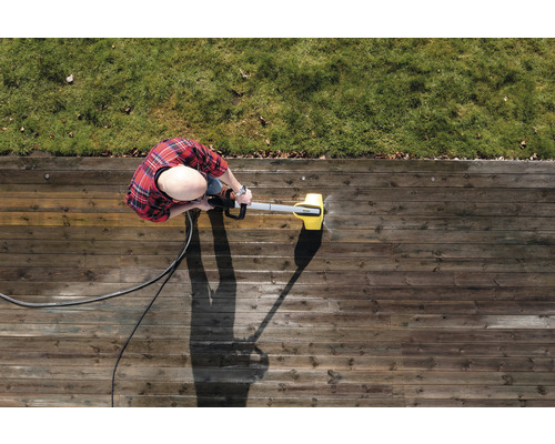 Person rengör träterrass med högtryckstvätt