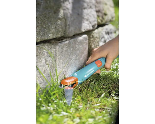 Gardena grässax används för att trimma gräsmattans kanter bredvid en stenmur.