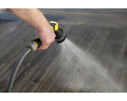 Person vattnar trägolv med trädgårdsslang och sprutpistol