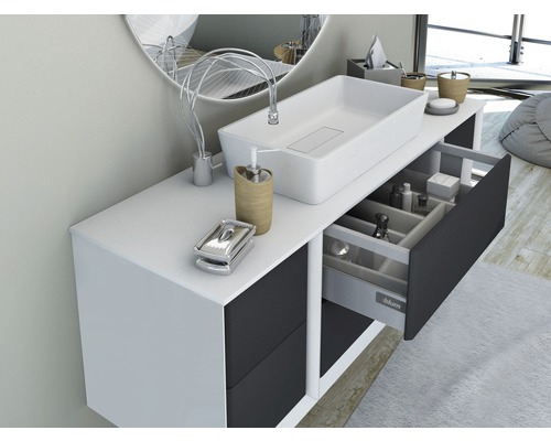 Modernt badrum med handfat, underskåp och öppen låda för förvaring av badrumsartiklar.