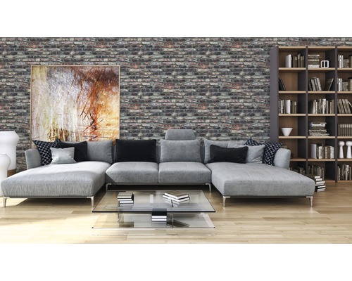 Vardagsrum med grå soffa, bokhylla och vägg med tegelstensutseende.