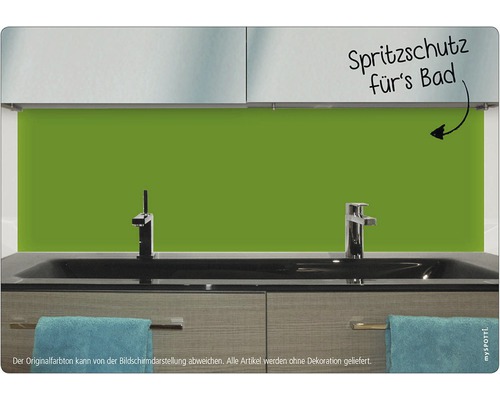Badrum med ett grönt stänkskydd bakom handfatet.