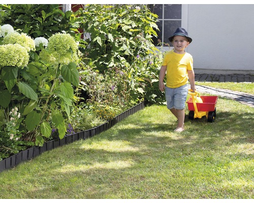 Trädgårdsscen med gräsmattskant och ett barn som drar en vagn