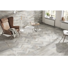 Ljust vardagsrum med kakelgolv i fiskbensmönster, fåtölj och golvlampa