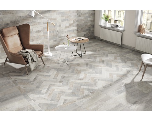 Ljust vardagsrum med kakelgolv i fiskbensmönster, fåtölj och golvlampa