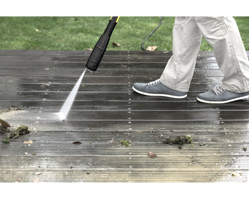 En person rengör en träterrass med en högtryckstvätt.