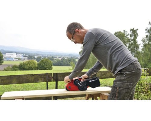 En person slipar trä med en bandslip från Einhell.