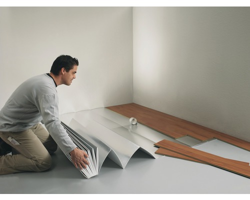 En man lägger laminatgolv med stegljudsdämpning i ett rum.