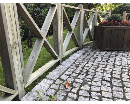 Trädgårdsstaket av trä med X-formad design bredvid blomlåda