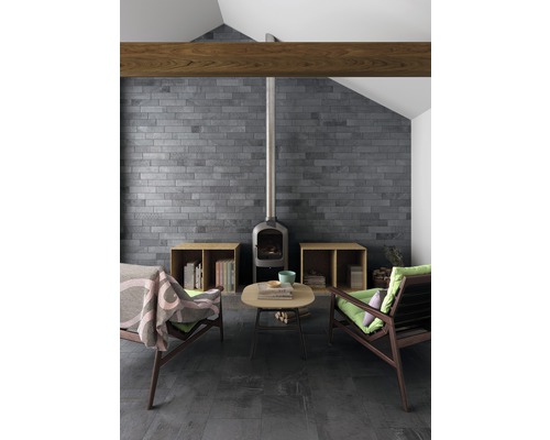 Vardagsrum med öppen spis, två fåtöljer, soffbord, kakelvägg och klinkergolv