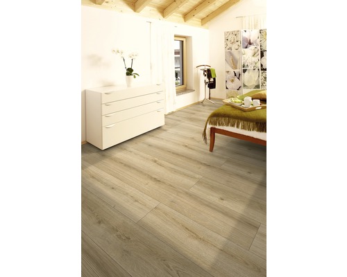 Ljust rum med laminatgolv i träutseende, byrå och säng