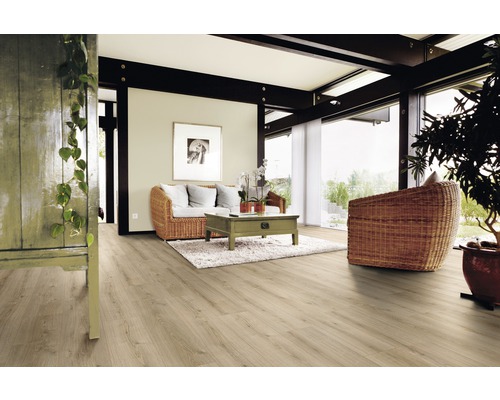 Ljust vardagsrum med trägolv, soffa och fåtölj av flätat material