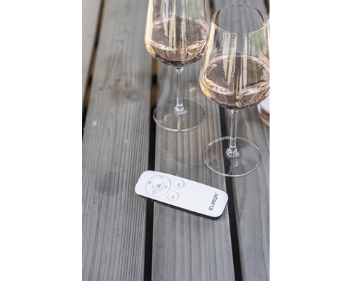 Två fyllda vinglas och en fjärrkontroll på ett träbord