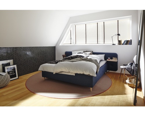 Sovrum med säng, matta och dekorativa element på en ljus vind