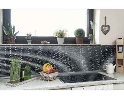 Köksscen med mosaikplattor, fönsterbräda med växter, fruktkorg och spishäll.