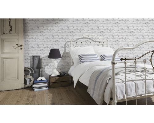 Ljust sovrum med säng framför tegelväggstapet