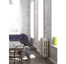 Ljust vardagsrum med matbord, stolar, soffa och radiator mot en tegelvägg