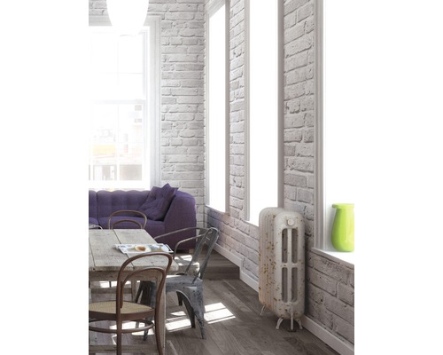 Ljust vardagsrum med matbord, stolar, soffa och radiator mot en tegelvägg