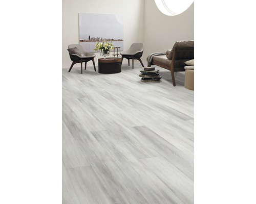 Ljust vardagsrum med laminatgolv i trälook, två stolar, soffa och dekorationer.