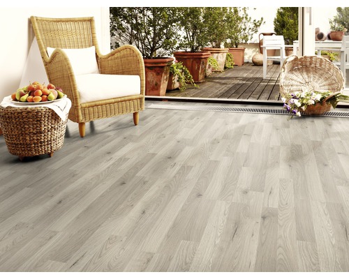 Ljust rum med laminatgolv, rottingfåtölj och krukväxter på balkongen