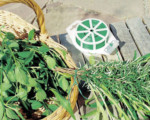 Växttråd och korg med färska örter på träbord