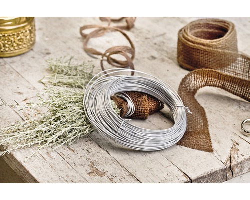 Dekorationsscen med bindtråd, juteband och gröna grenar på ett träbord