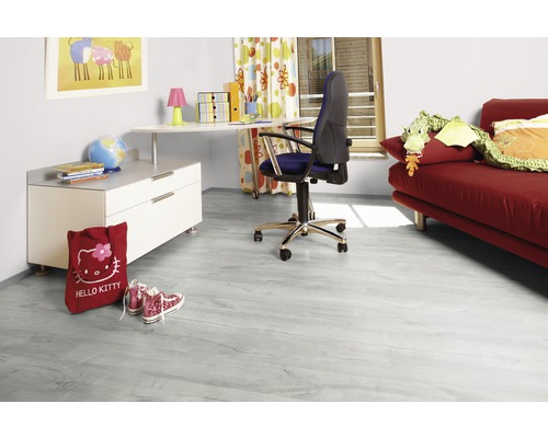 Barnvänligt rum med ljust laminatgolv, skrivbord, stol och röd soffa