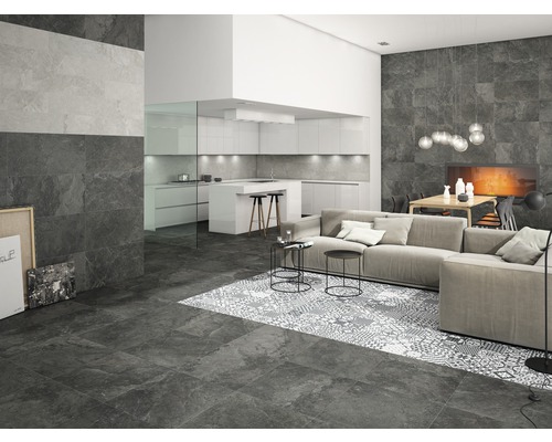 Vardagsrum med golv- och väggplattor i stenlook, soffa och öppet kök
