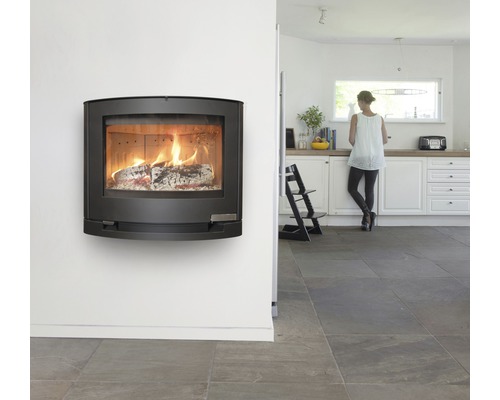 Väggmonterad eldstad med brinnande ved i ett ljust rum